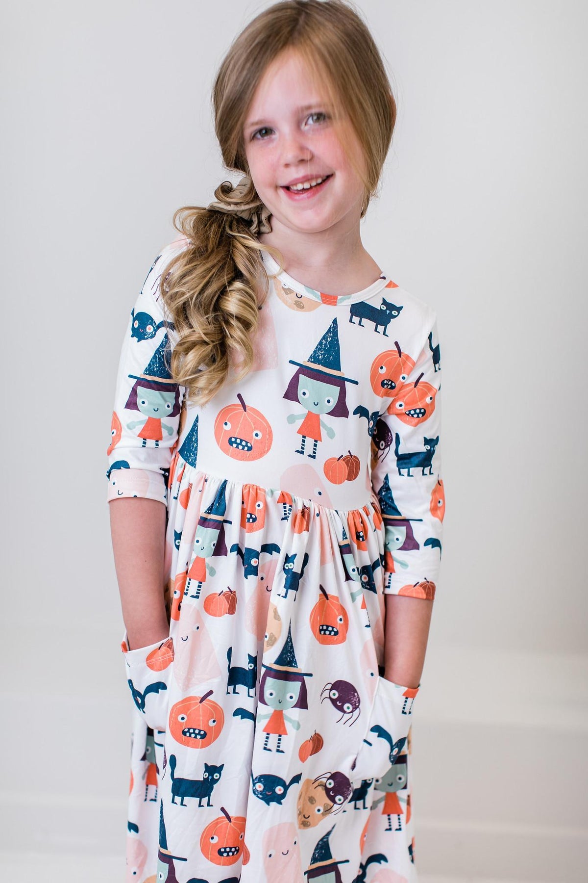 Girl with a hand in the side pocket of the Boo Crew twirl dress, full length.