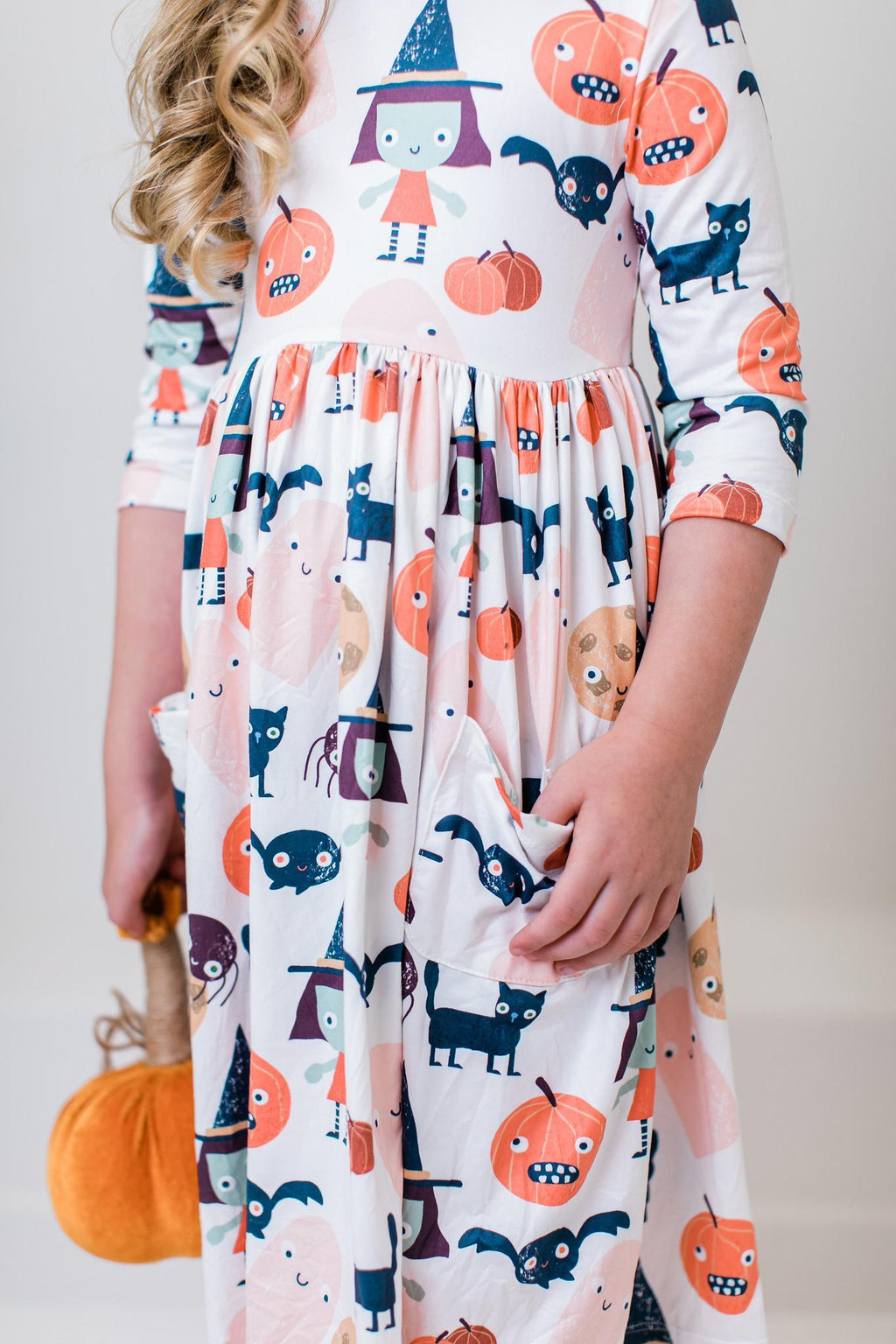 Close-up of the Boo Crew twirl dress showing a side pocket and the printed jack-o'-lanterns, ghosts, cats and bats.