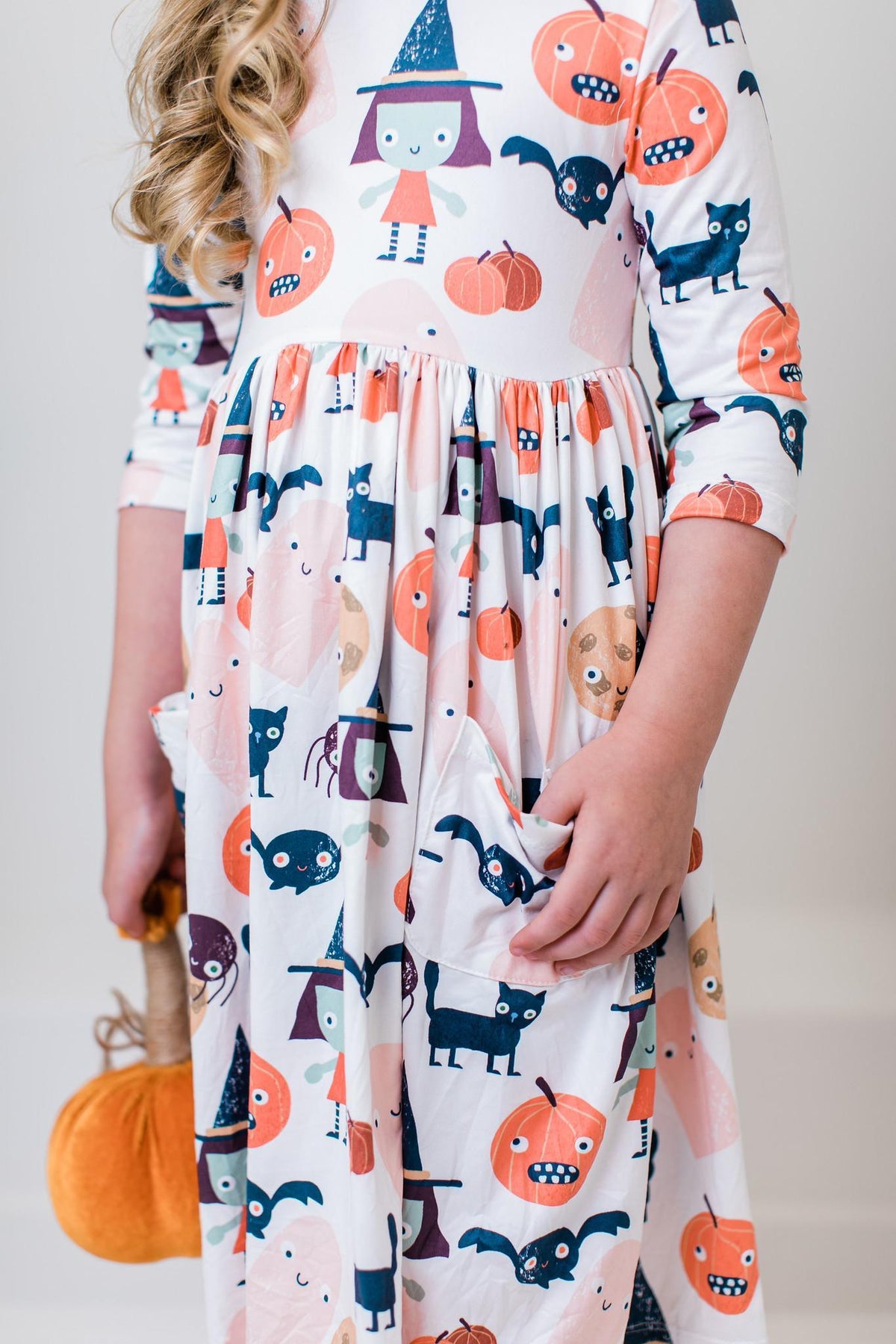 Close-up of the Boo Crew twirl dress showing a side pocket and the printed jack-o'-lanterns, ghosts, cats and bats.
