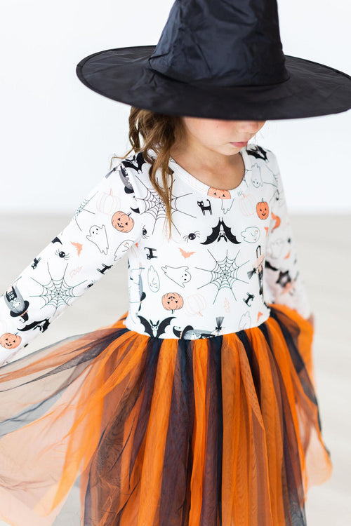 Close-up of the Boo-tiful Halloween dress: white bodice print with bats, ghosts, spiders and pumpkin faces, a long sleeve, and gathered orange and black tulle skirt layers.