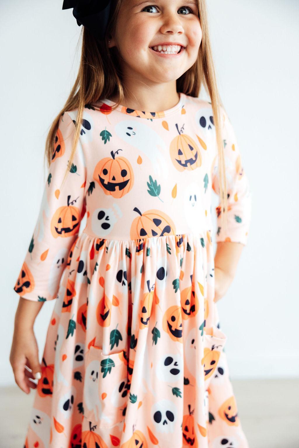 Close-up of the sleeve, bodice and skirt of the Pumpkin Peekaboo twirl dress worn by a girl.