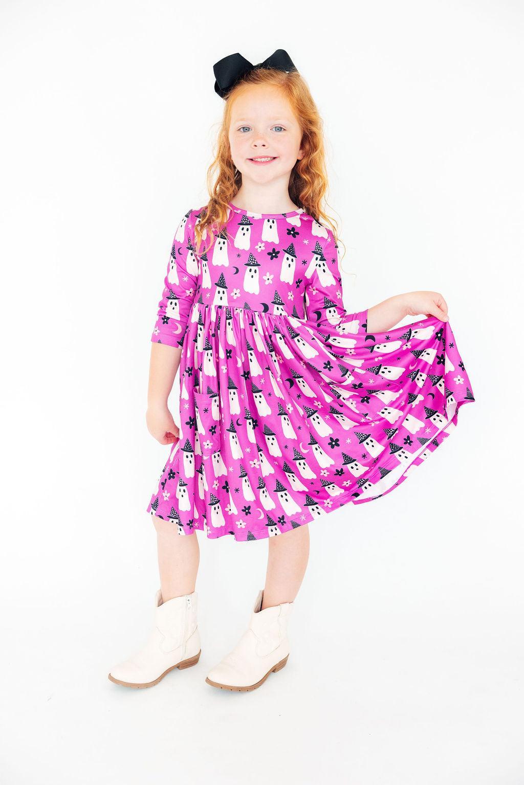 Girl twirling so the skirt of the Witches Boo twirl dress fans out, with white boots.