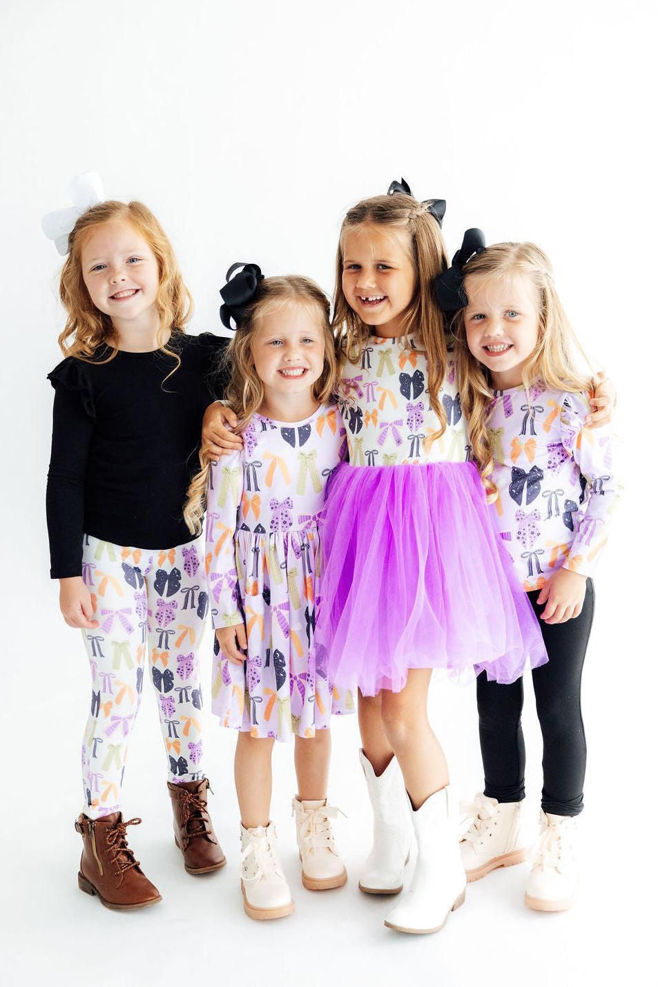 Three girls wearing the Tied with a Boo leggings with black tops, one layered under a purple tutu.